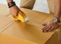 crop man sealing box with scotch tape