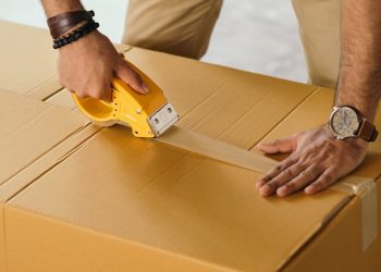 crop man sealing box with scotch tape